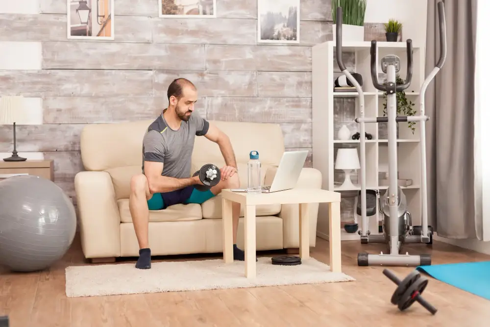 A fit man doing home workouts to burn calories using dumbbells